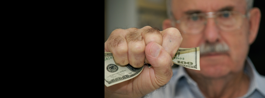 An old man clenching a $100 dollar bill.
