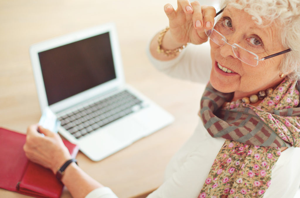 Old woman with credit card in front of her laptop looking at you